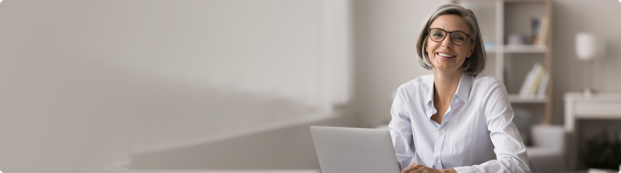Mujer de mediana edad sonriendo a la computadora portátil