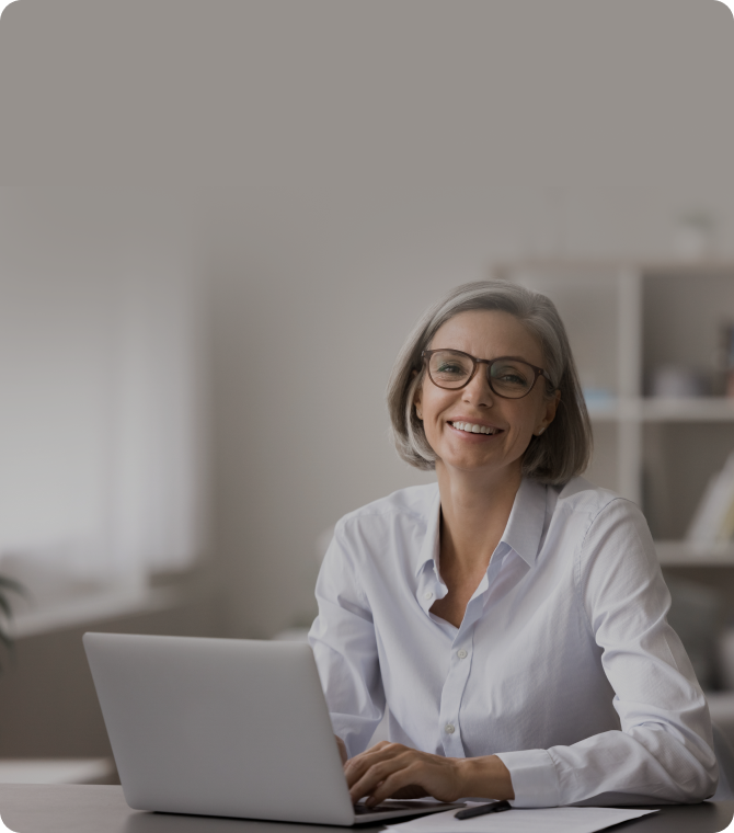 Mujer de mediana edad sonriendo a la computadora portátil