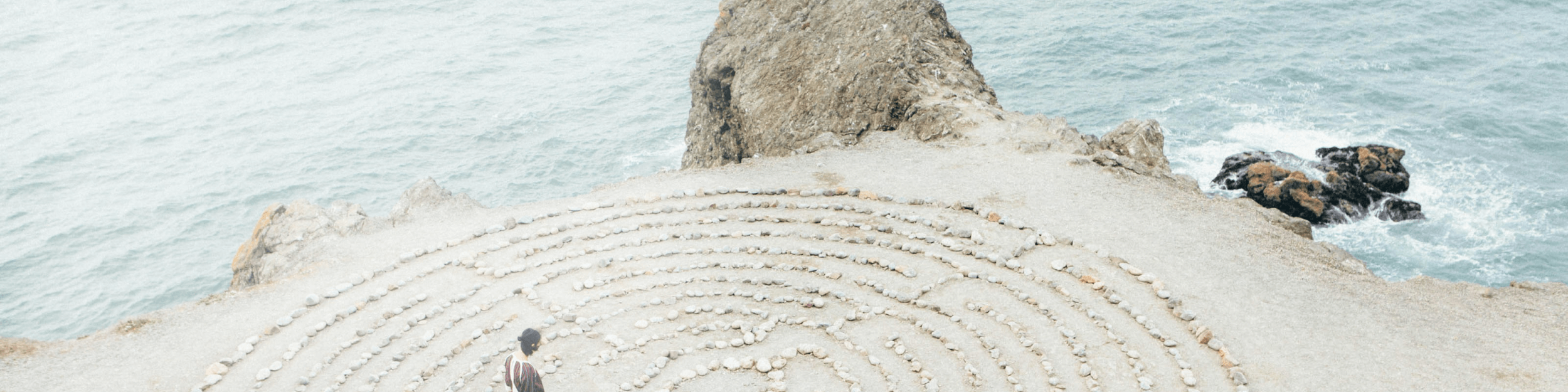 Mujer caminando por un laberinto de piedra en la playa